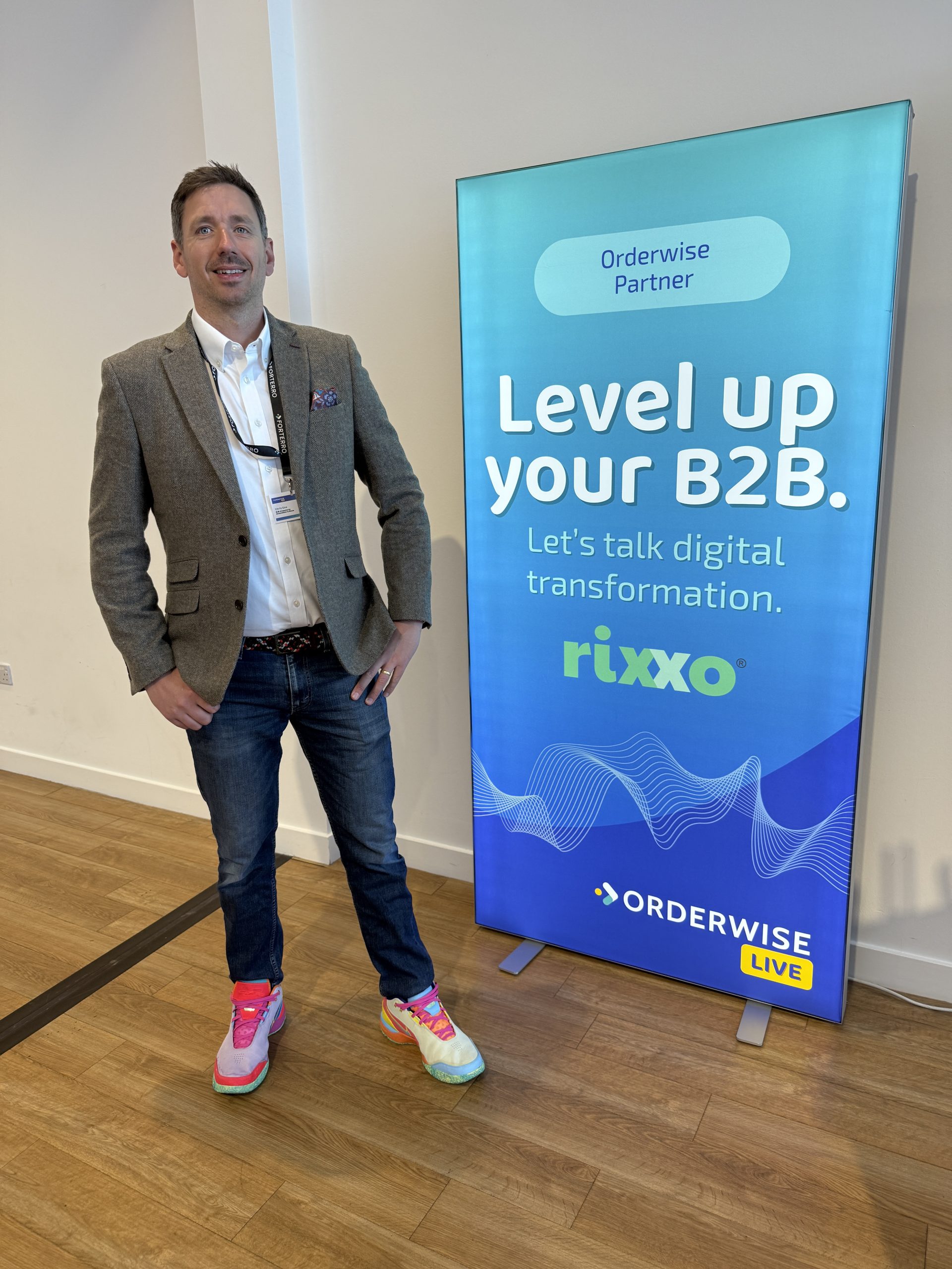 Man at Orderwise Live event, wearing smart-casual outfit and vibrant mismatched sneakers.